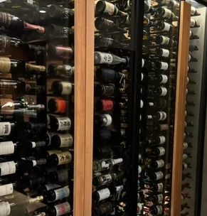 Close-up of a person selecting a wine bottle from a wine rack